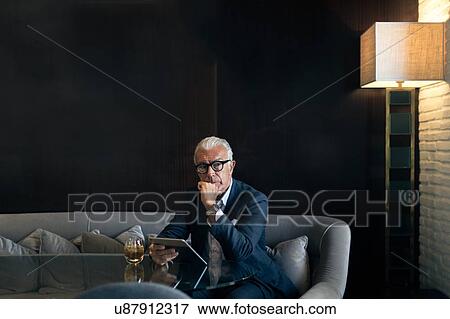 Senior businessman sitting in hotel table using digital tablet, portrait View Large Photo Image Stock Photo - Senior businessman sitting in hotel table using digital tablet, portrait. Fotosearch