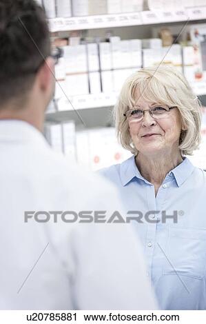Senior female customer talking to male pharmacist in pharmacy. View Large Photo Image Stock Image - Senior female customer talking to male pharmacist in pharmacy.. Fotosearch