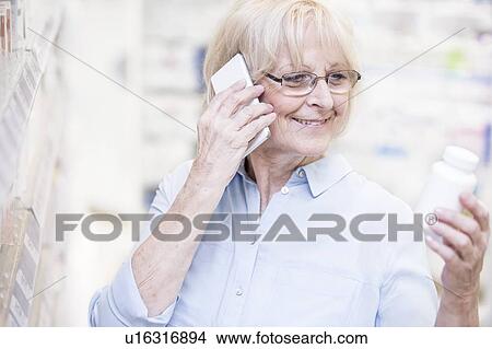 Senior woman discussing medicine on mobile phone in pharmacy. View Large Photo Image Picture - Senior woman discussing medicine on mobile phone in pharmacy.. Fotosearch