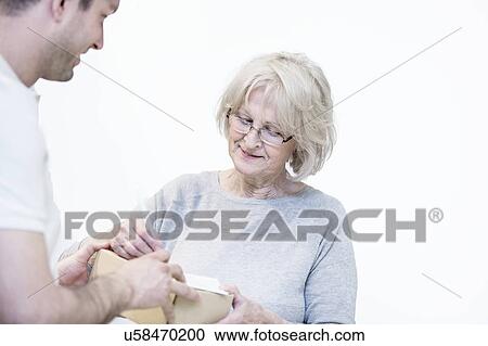 Senior woman signing for delivery from courier. View Large Photo Image Stock Image - Senior woman signing for delivery from courier.. Fotosearch