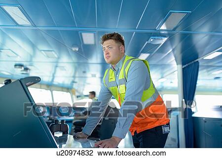 Stock Image - Ship worker on bridge of ship. Fotosearch