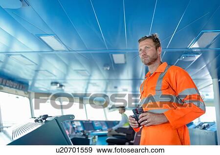 Stock Photo - Ship worker with binoculars on bridge of ship. Fotosearch