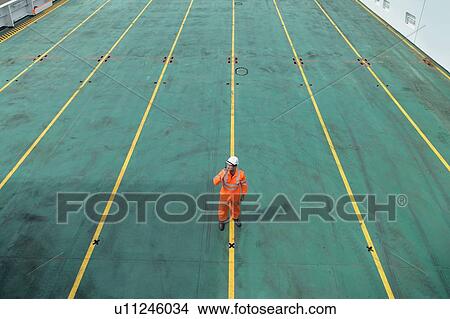 Picture - Ship's worker using walkie talkie on deck of ship in port. Fotosearch