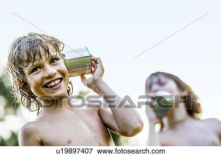Stock Photo - Shirtless boys playing with tin can phone, listening.. Fotosearch