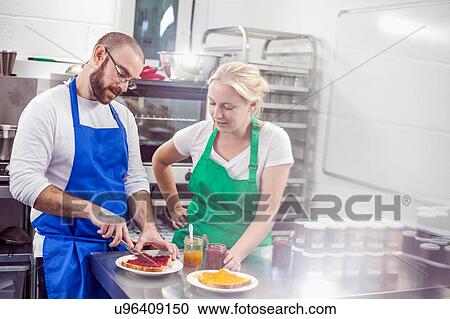 Stock Image - Small business owners tasting fresh jam on toast in industrial kitchen. Fotosearch