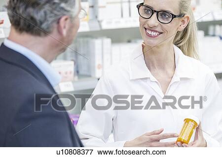 Smiling female pharmacist explaining medication to customers in pharmacy. View Large Photo Image Stock Photo - Smiling female pharmacist explaining medication to customers in pharmacy.. Fotosearch