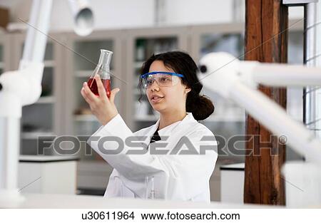 Picture - Student analysing sample in flask in laboratory. Fotosearch
