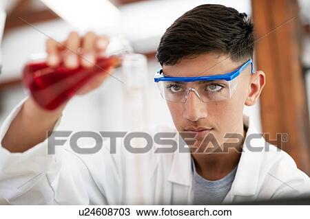Stock Image - Student pouring sample into flask in laboratory. Fotosearch