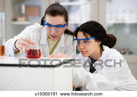 Stock Image - Students analysing sample in flask in laboratory. Fotosearch