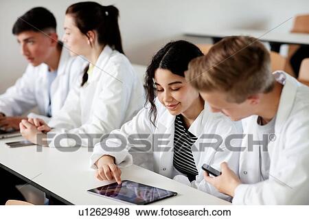 Stock Photo - Students using digital tablet in classroom. Fotosearch