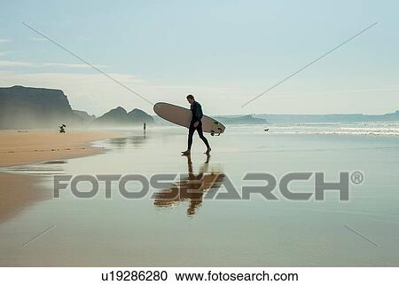 Surfer carrying surfboard on beach, Watergate Bay, Cornwall, UK View Large Photo Image Stock Image - Surfer carrying surfboard on beach, Watergate Bay, Cornwall, UK. Fotosearch