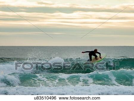 Stock Photograph - Surfer riding on ocean wave, Watergate Bay, Cornwall, UK. Fotosearch