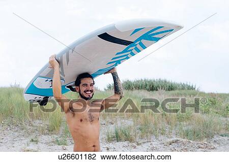 Stock Image - Surfer with surfboard by seaside. Fotosearch