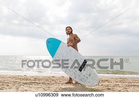 Stock Photo - Surfer with surfboard by seaside. Fotosearch