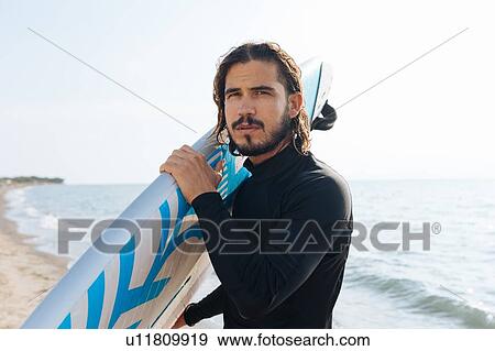 Stock Photo - Surfer with surfboard by seaside. Fotosearch