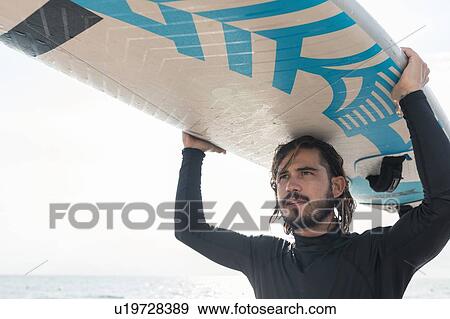 Stock Photo - Surfer with surfboard by seaside. Fotosearch