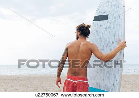 Surfer with surfboard by seaside View Large Photo Image Stock Photo - Surfer with surfboard by seaside. Fotosearch
