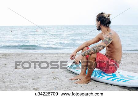 Stock Photo - Surfer with surfboard by seaside. Fotosearch