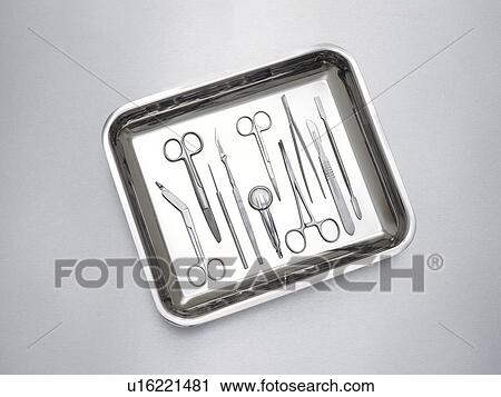 Stock Image - Surgical equipment in a tray against a grey background.. Fotosearch
