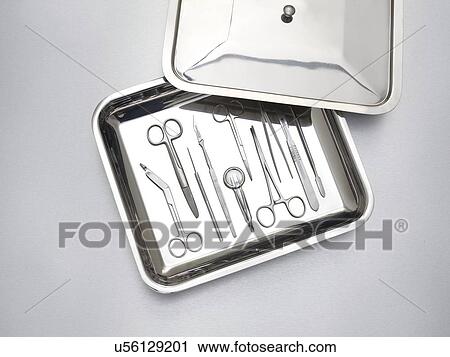 Stock Image - Surgical equipment in a tray against a grey background.. Fotosearch
