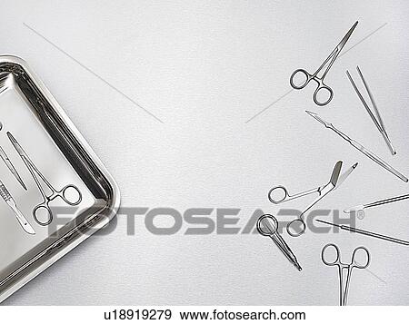 Stock Photo - Surgical scissors and tray against a grey background.. Fotosearch