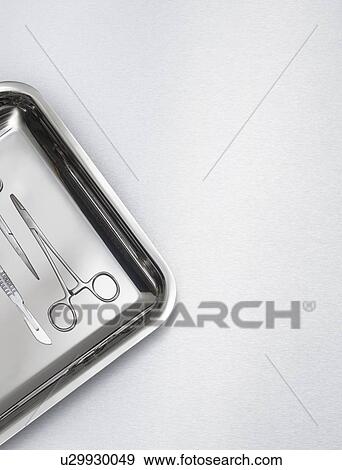 Stock Photo - Surgical scissors on a tray against a grey background.. Fotosearch