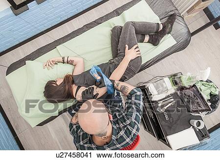 Stock Image - Tattooist drawing on arm of client. Fotosearch