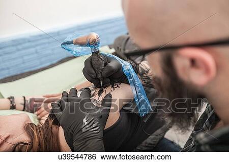 Stock Photograph - Tattooist drawing on arm of client. Fotosearch