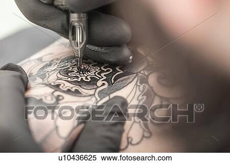 Stock Photography - Tattooist drawing on arm of client. Fotosearch