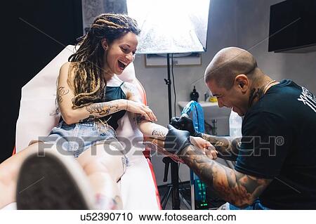 Stock Image - Tattooist drawing on arm of customer. Fotosearch