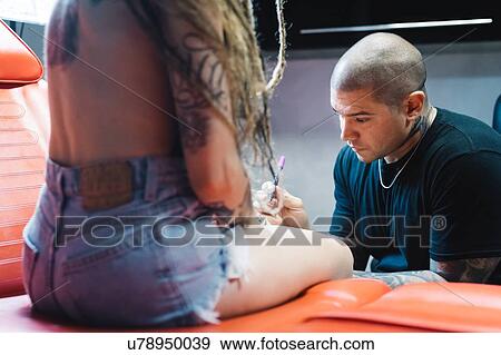 Tattooist drawing on arm of customer View Large Photo Image Stock Photo - Tattooist drawing on arm of customer. Fotosearch