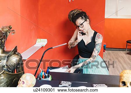Tattooist talking on mobile phone in parlour View Large Photo Image Stock Image - Tattooist talking on mobile phone in parlour. Fotosearch