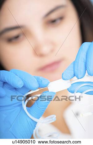 Stock Image - Technician working with a microfluidic lab on a chip device.. Fotosearch