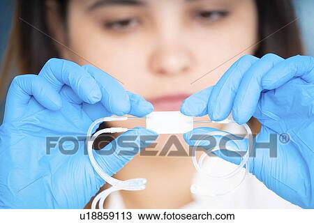Stock Image - Technician working with a microfluidic lab on a chip device.. Fotosearch