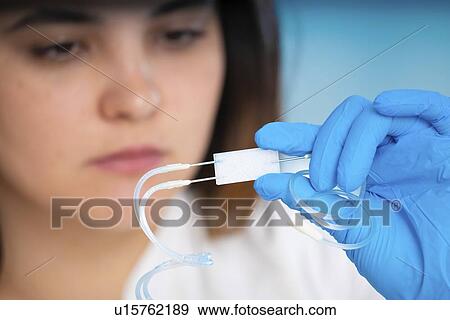 Stock Photo - Technician working with a microfluidic lab on a chip device.. Fotosearch