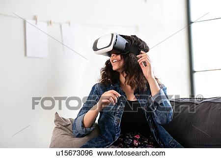 Teenage girl on sofa looking through virtual reality headset View Large Photo Image Stock Photograph - Teenage girl on sofa looking through virtual reality headset. Fotosearch