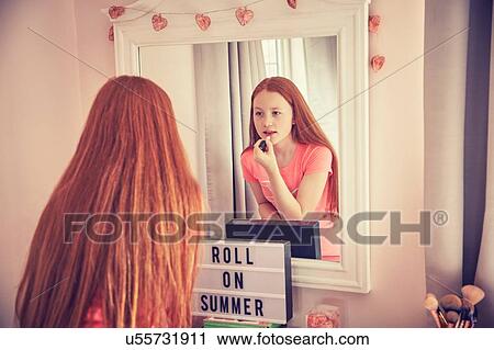 Stock Image - Teenage girl putting on make-up. Fotosearch
