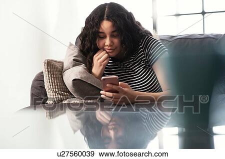 Teenage girl sitting on sofa looking at smartphone View Large Photo Image Stock Photo - Teenage girl sitting on sofa looking at smartphone. Fotosearch