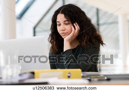 Stock Image - Teenage schoolgirl at classroom desk looking at laptop. Fotosearch
