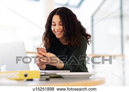 Teenage schoolgirl at classroom desk looking at smartphone View Large Photo Image Stock Photo - Teenage schoolgirl at classroom desk looking at smartphone. Fotosearch