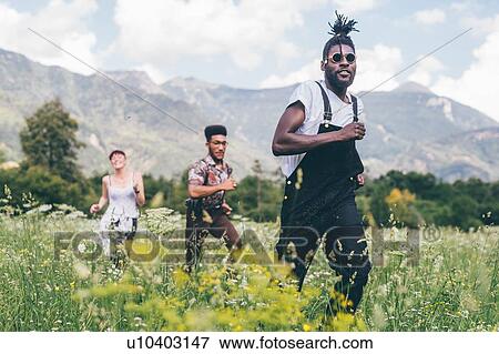 Stock Photo - Three adult friends racing through wildflower meadow, Primaluna, Trentino-Alto Adige, Italy. Fotosearch