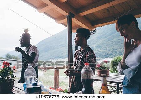 Stock Photography - Three young adult friends taking a break on rural porch. Fotosearch