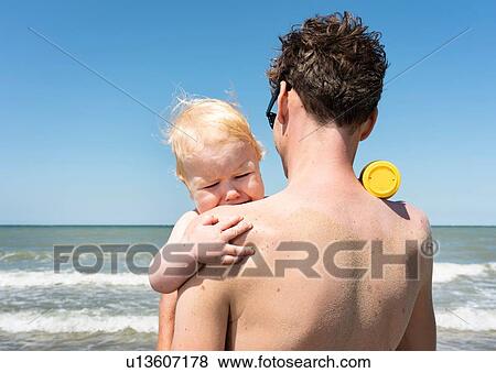 Toddler finds comfort with father on beach View Large Photo Image Stock Photo - Toddler finds comfort with father on beach. Fotosearch