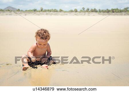 Toddler playing in sand on beach View Large Photo Image Stock Photo - Toddler playing in sand on beach. Fotosearch