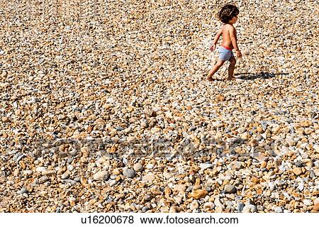 Toddler walking on pebble beach View Large Photo Image Stock Photo - Toddler walking on pebble beach. Fotosearch