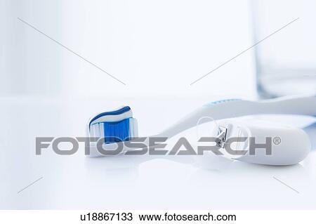 Stock Image - Toothbrush with toothpaste and dental floss against a white background.. Fotosearch