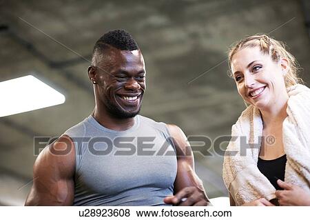 Stock Photo - Trainer and female client laughing in gym. Fotosearch