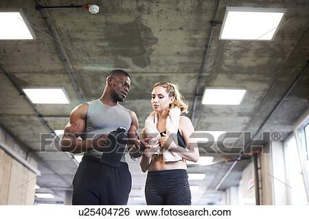 Trainer and female client talking in gym View Large Photo Image Stock Photograph - Trainer and female client talking in gym. Fotosearch