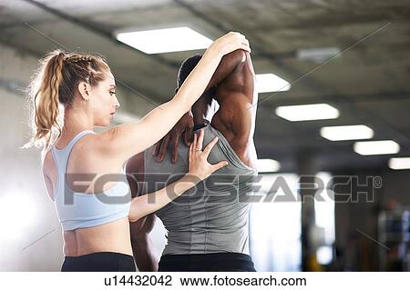 Trainer helping man with stretching exercise in gym View Large Photo Image Stock Image - Trainer helping man with stretching exercise in gym. Fotosearch