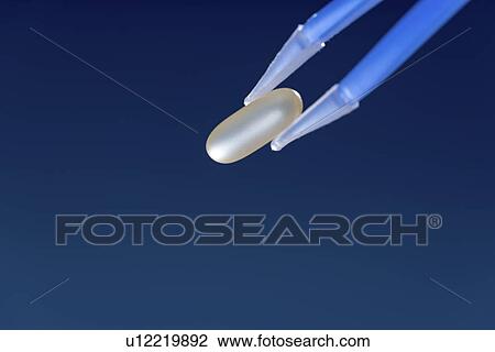 Stock Image - Tweezers holding capsule.. Fotosearch